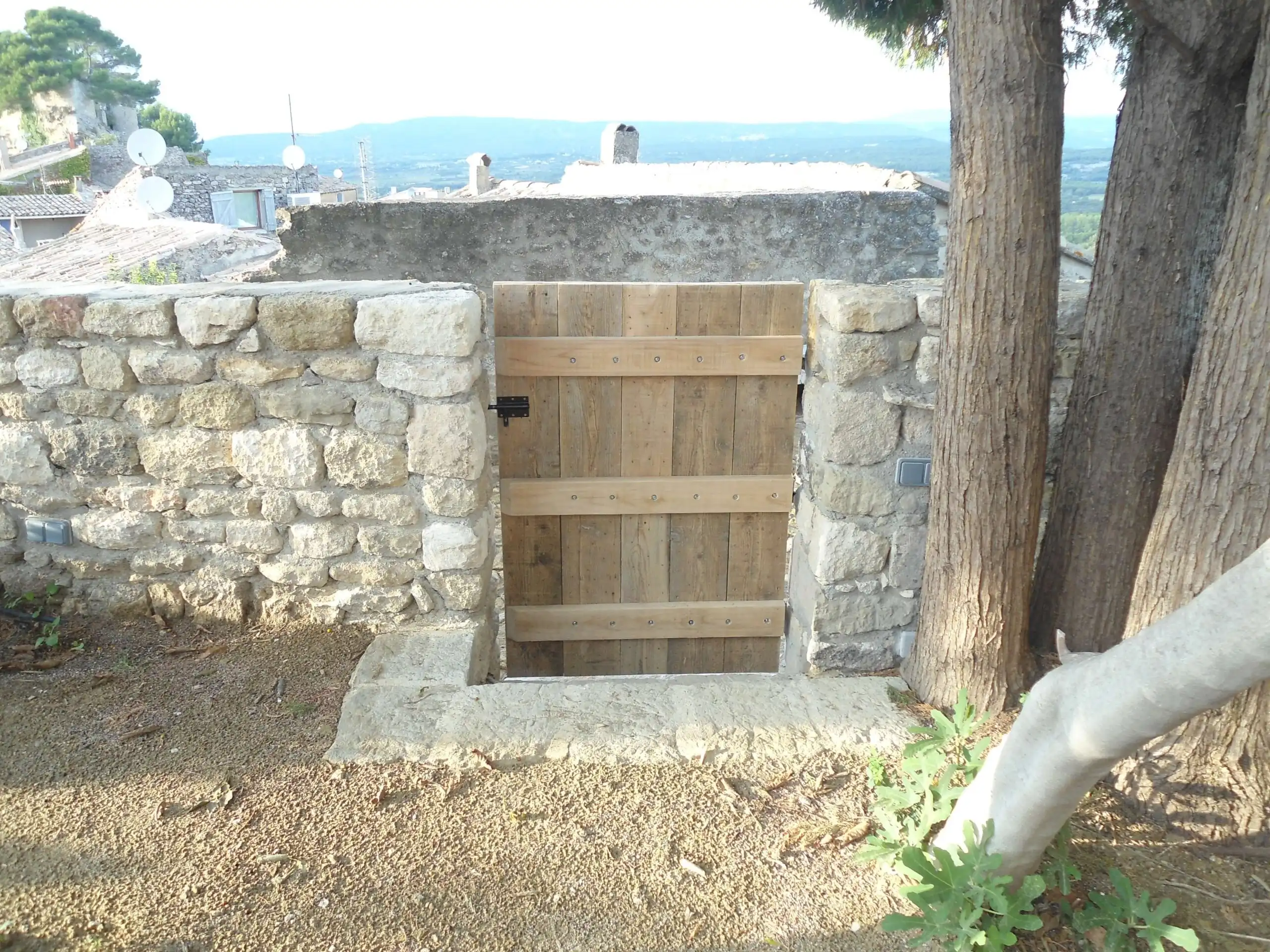Muret en pierre naturelle avec portillon en bois réalisé lors de travaux d’aménagement extérieur