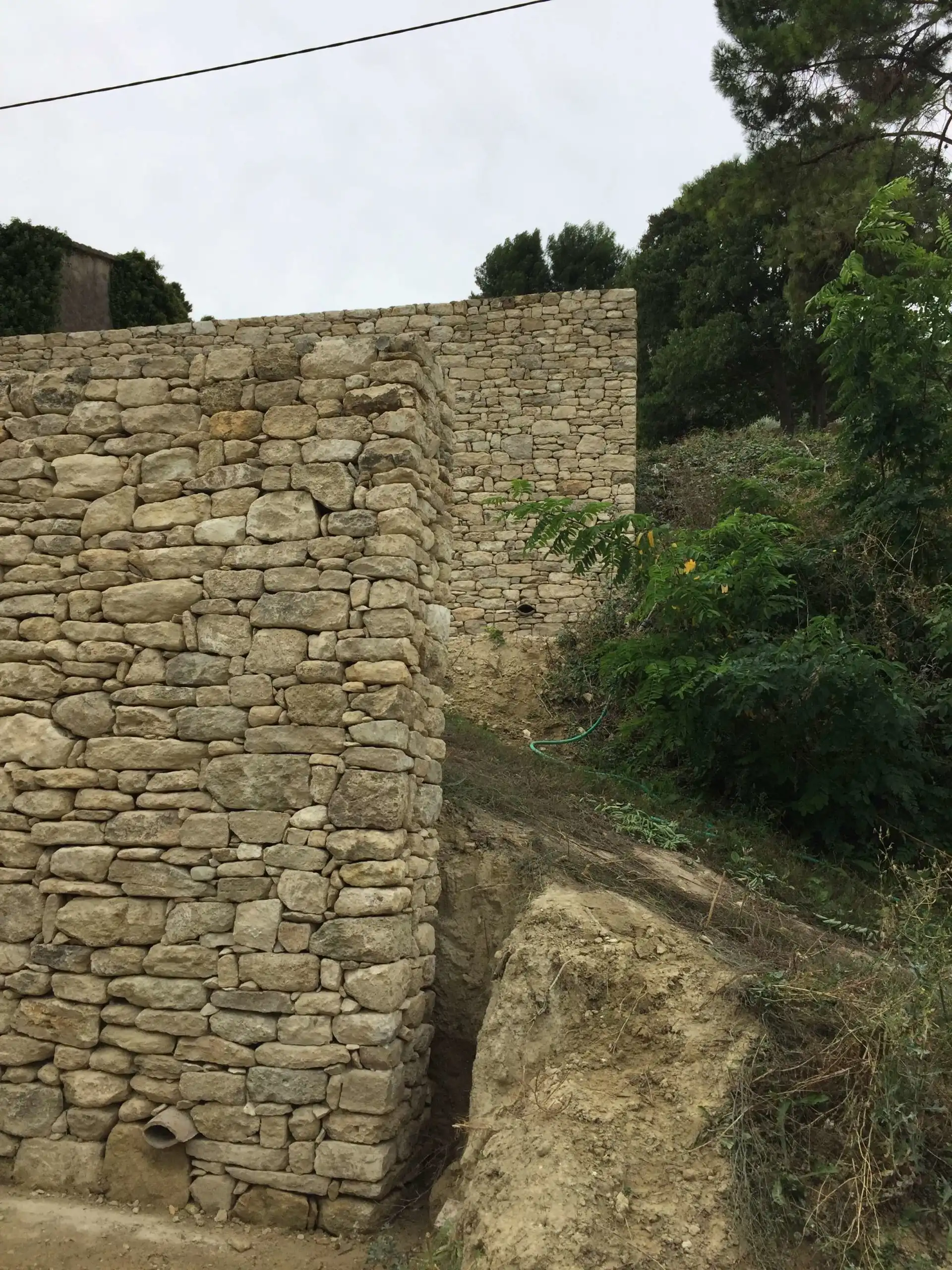 Angle de mur de soutènement en pierre sèche réalisé sur un terrain en pente à Ménerbes.