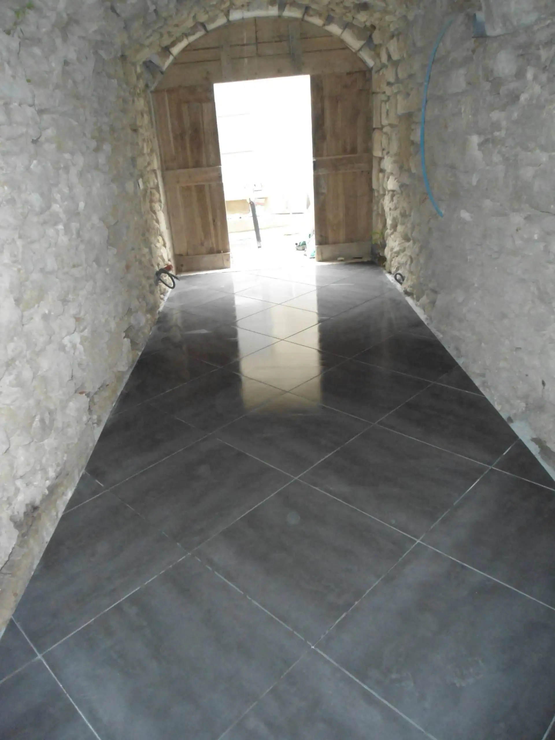 Pose de carrelage grand format dans une cave voûtée en pierre rénovée