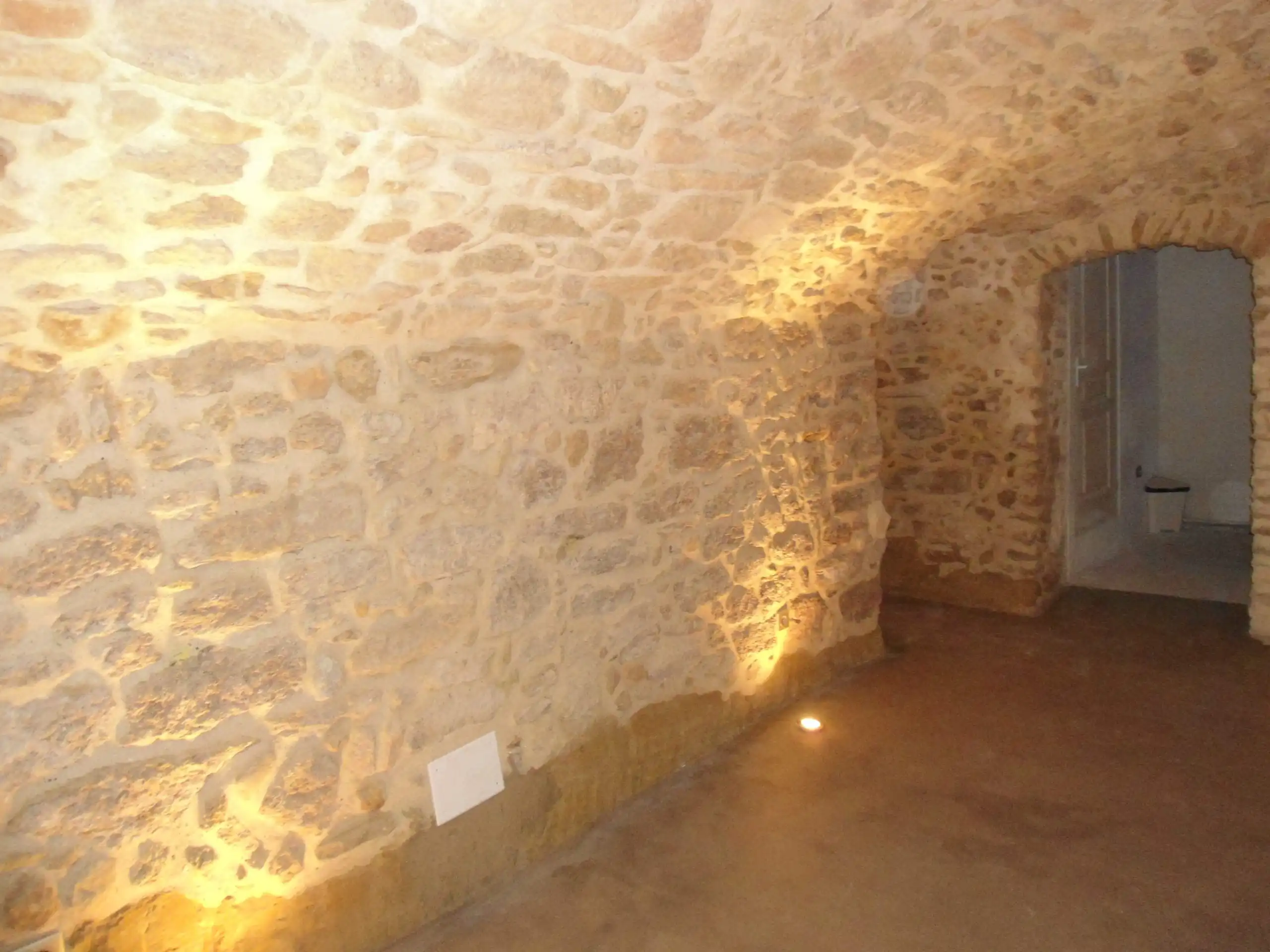 Cave voûtée rénovée avec éclairage intégré mettant en valeur les murs en pierre apparente
