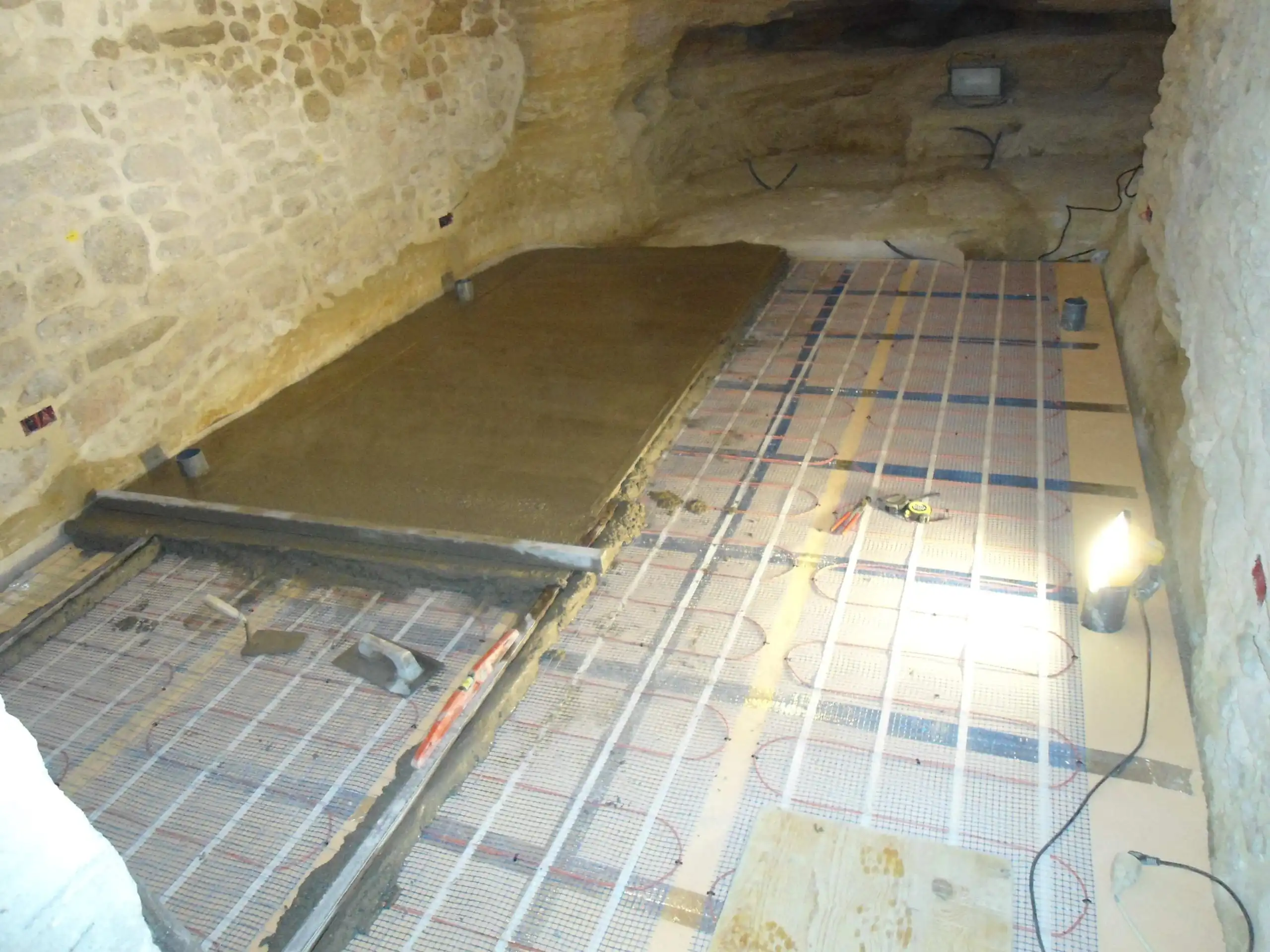 Installation d’un chauffage au sol dans une cave en pierre en cours de rénovation