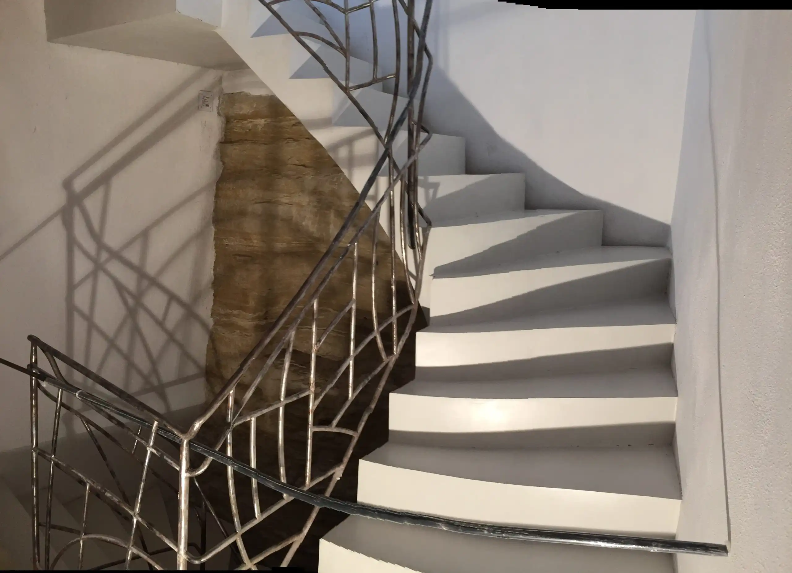 Escalier courbe en béton avec garde-corps métallique sur mesure dans une rénovation intérieure