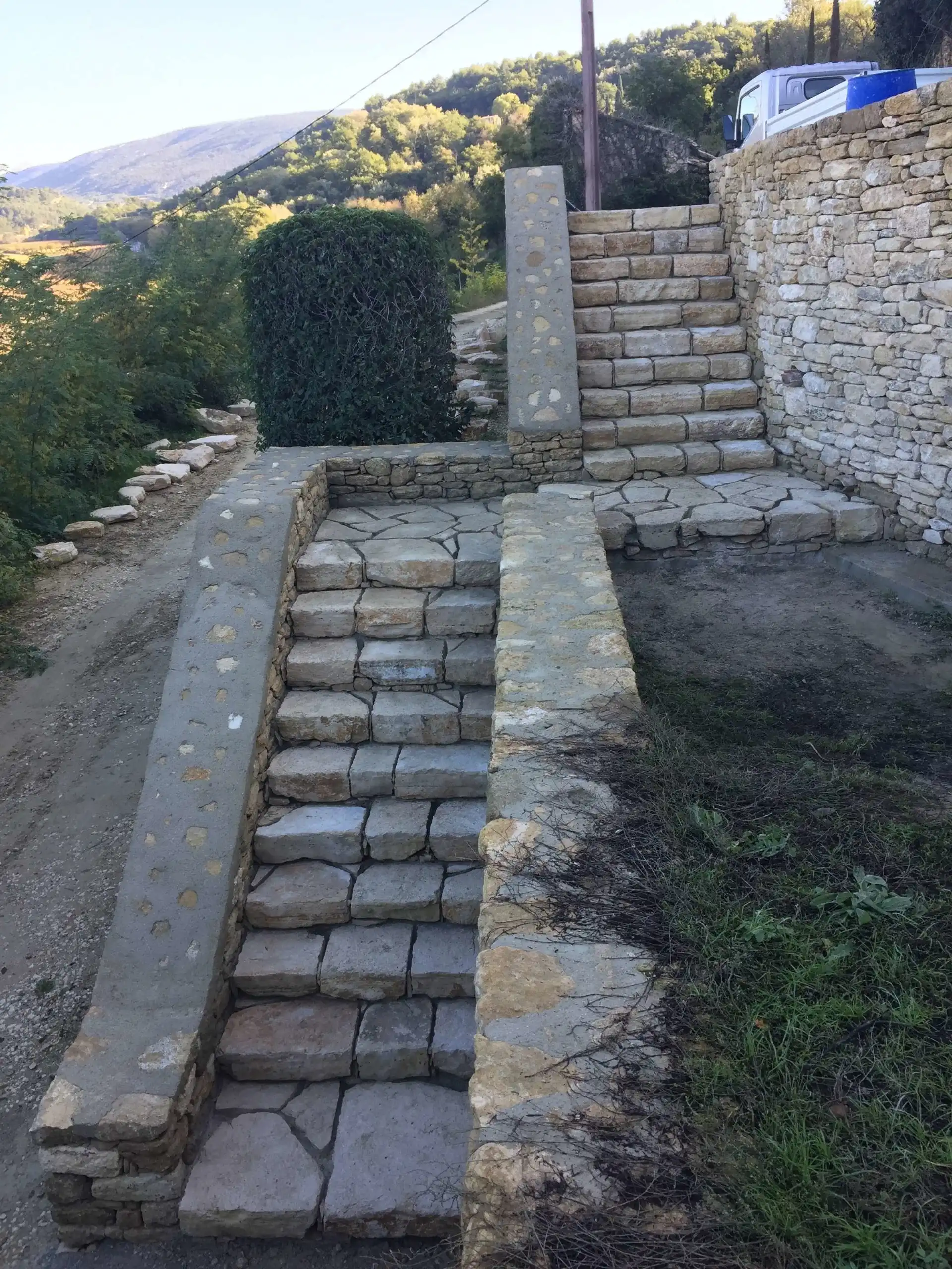 Escaliers en pierre naturelle intégrés à un mur de soutènement dans un aménagement paysager du Luberon.