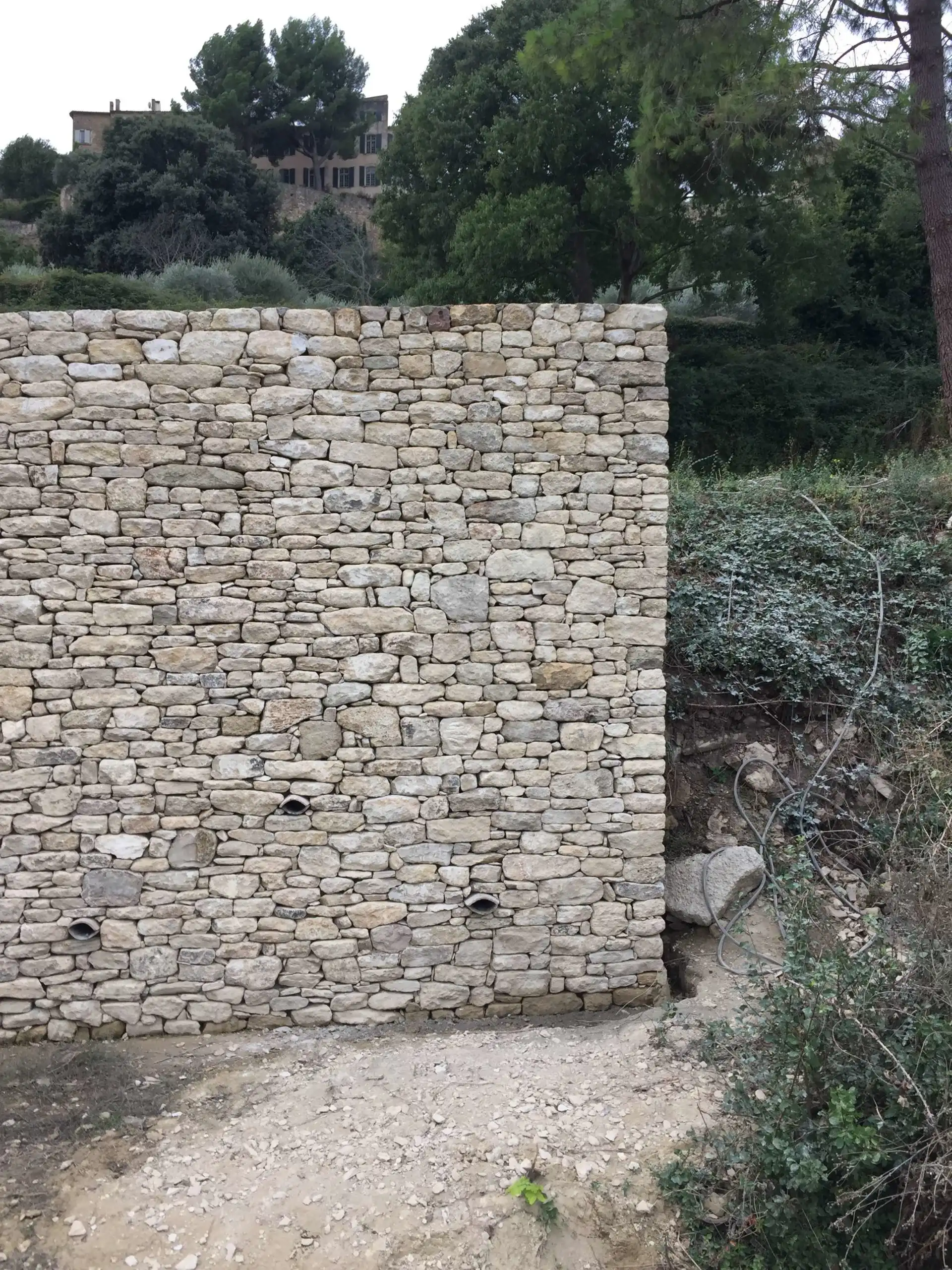 Mur de soutènement en pierre sèche avec drains intégrés réalisé sur un terrain en pente à Ménerbes.