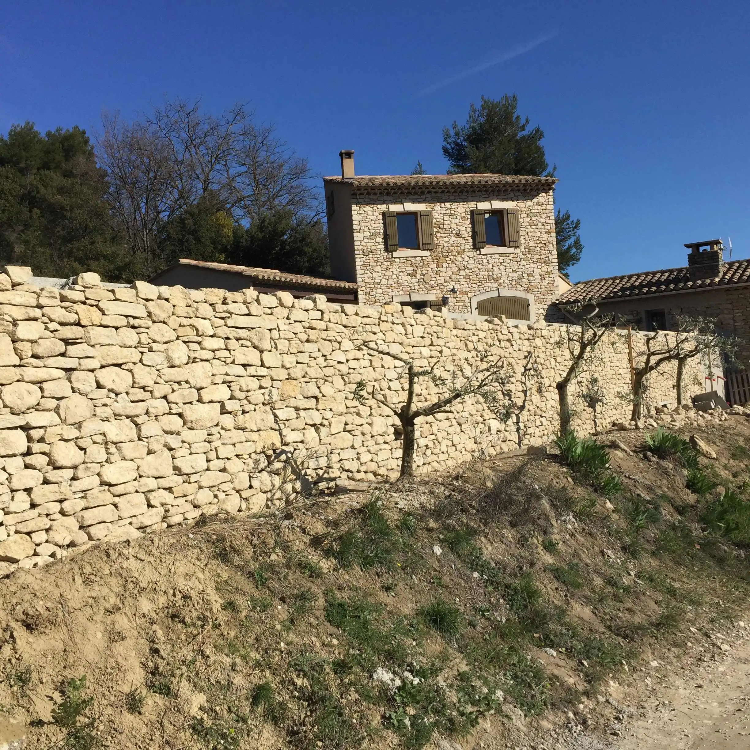 Mur de soutènement en pierre sèche réalisé pour retenir un terrain en pente dans le Luberon.