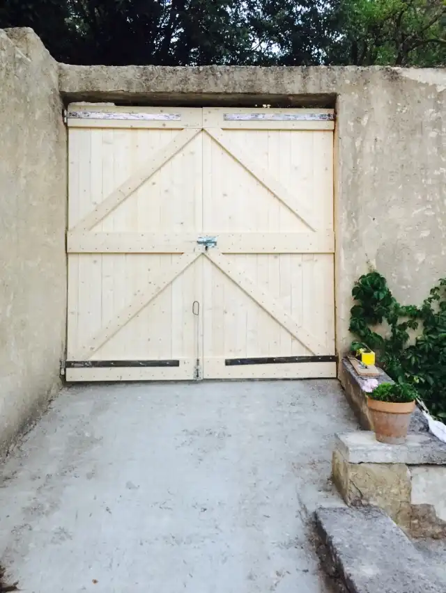 Portail double battant en bois massif fabriqué sur mesure pour une propriété en pierre