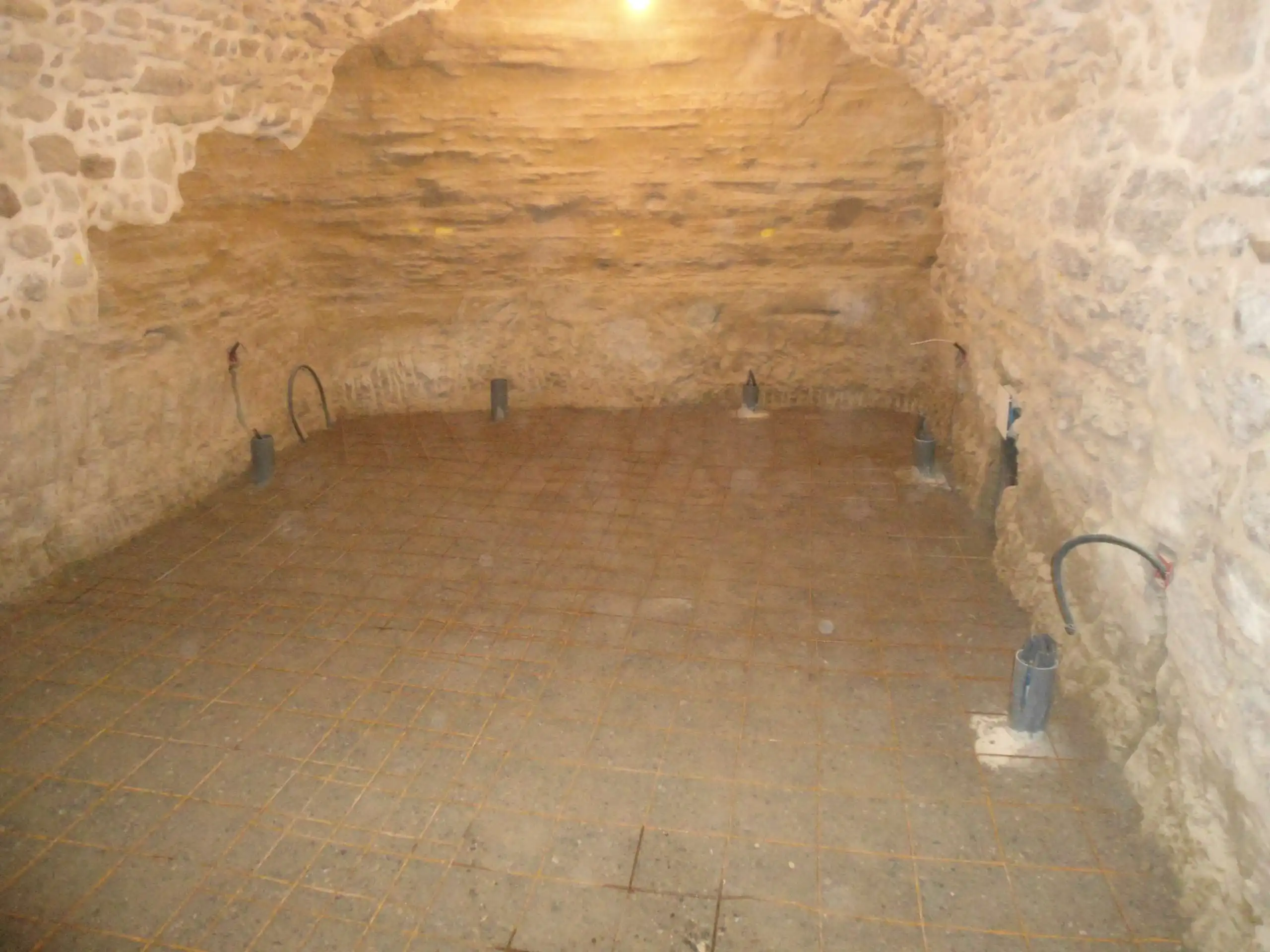 Cave voûtée en pierre en cours de rénovation avec préparation de dalle et réseaux techniques