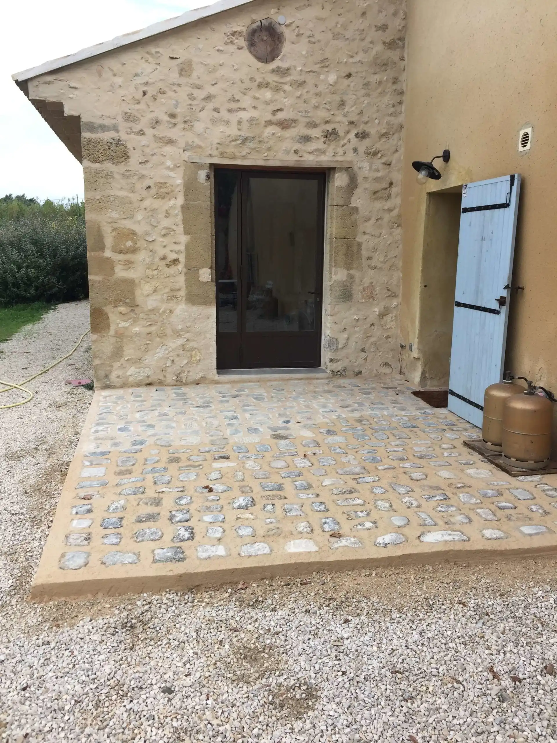 Terrasse en pierre réalisée devant une maison ancienne rénovée à Ménerbes
